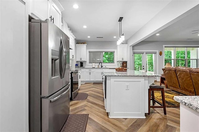 1505 Willis Rd, Barnesville, GA 30204 - kitchen with stainless steel appliances, open floor plan, white cabinetry, a center island, and a breakfast bar area