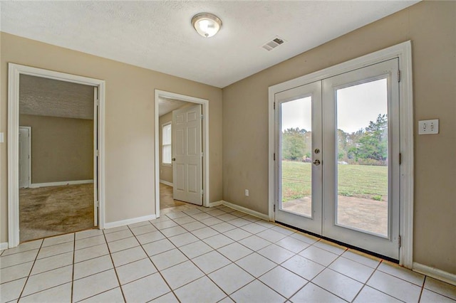 doorway with french doors, a textured ceiling, and light tile patterned flooring