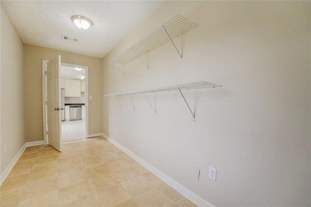 walk in closet with light tile patterned floors