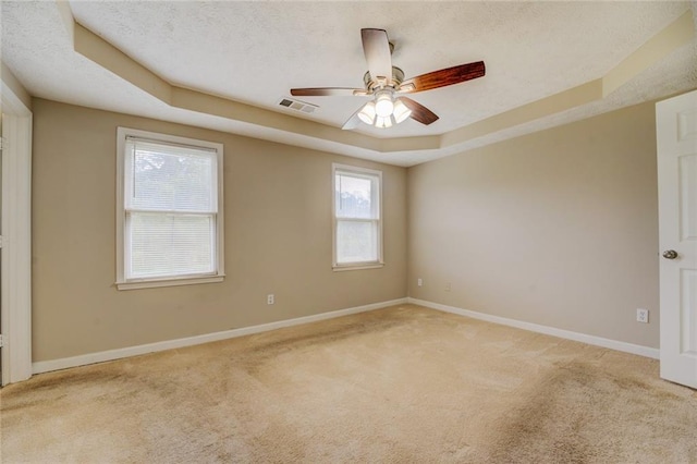 carpeted spare room featuring a textured ceiling, a raised ceiling, and ceiling fan