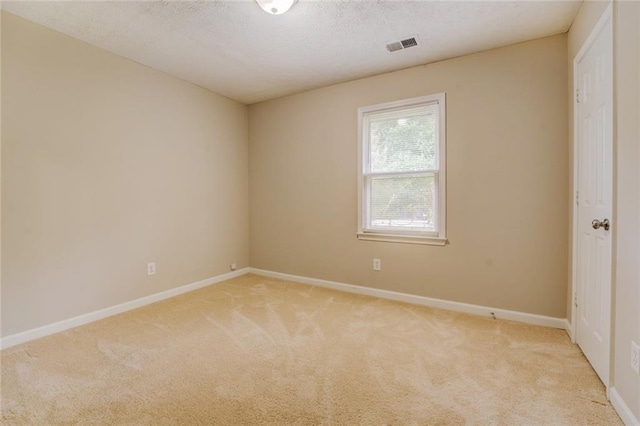 empty room with light colored carpet and a textured ceiling