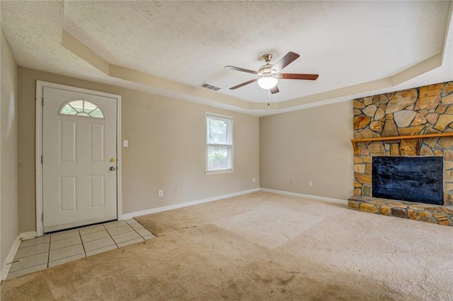 1187 Dixie Rd, Covington, GA 30014 - carpeted entryway featuring a tray ceiling, baseboards, a textured ceiling, a ceiling fan, and a fireplace