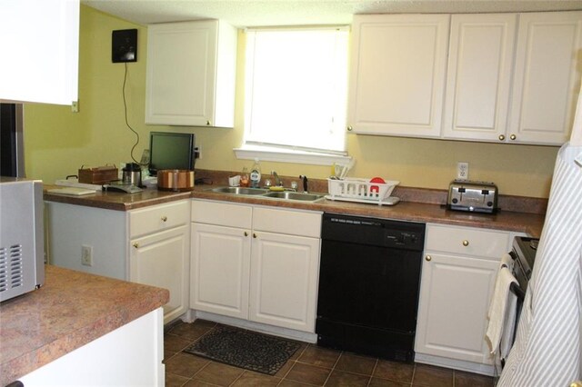 kitchen with sink, dark tile patterned floors, range, white cabinetry, and black dishwasher