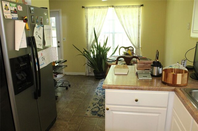 kitchen with white cabinetry, dark tile patterned flooring, and stainless steel fridge with ice dispenser