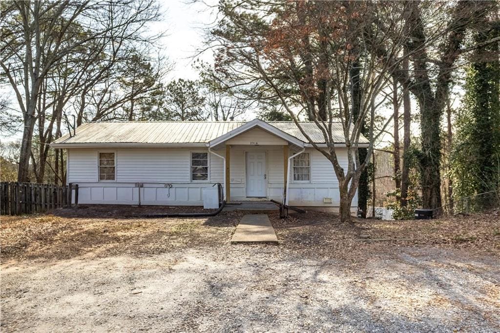 single story home featuring metal roof, covered porch, and fence