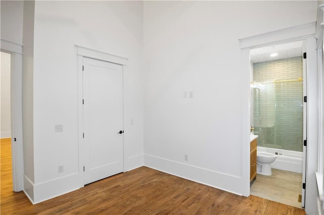 unfurnished bedroom with hardwood / wood-style floors and ensuite bathroom