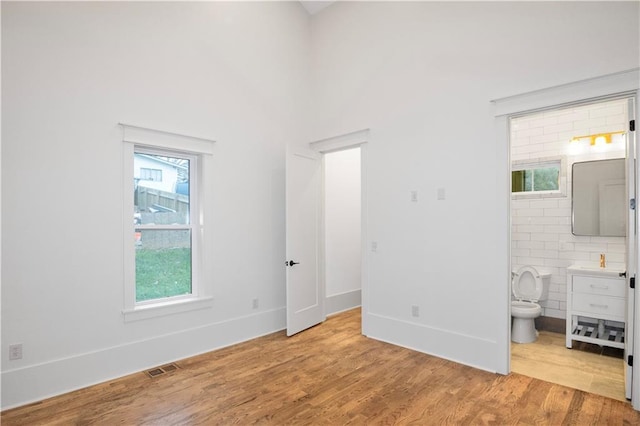 unfurnished bedroom with light wood-type flooring and connected bathroom