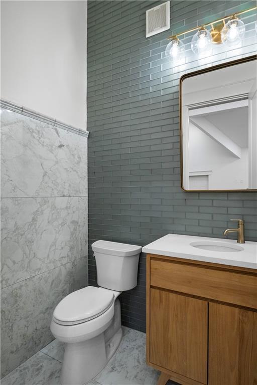 bathroom with vanity, toilet, and tile walls