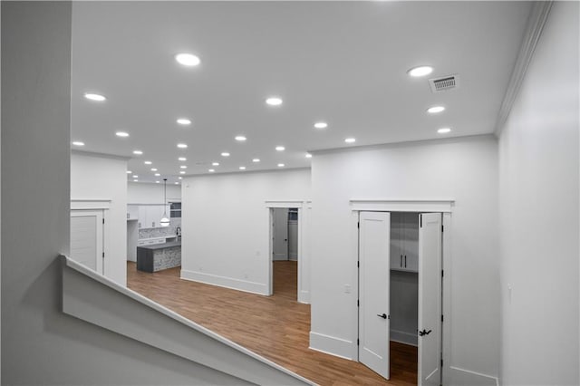 hallway featuring hardwood / wood-style floors and ornamental molding