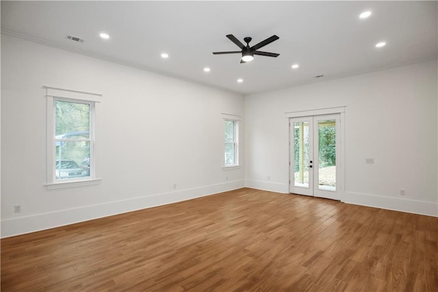 empty room with ceiling fan, crown molding, wood-type flooring, and french doors