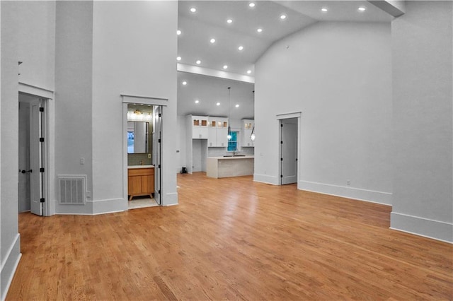 unfurnished living room with high vaulted ceiling and light hardwood / wood-style floors