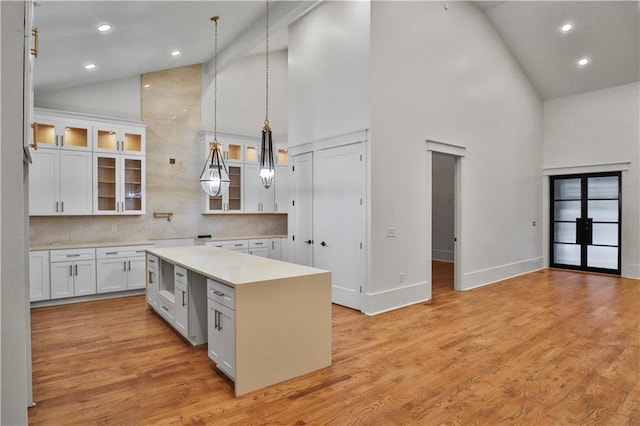 kitchen with pendant lighting, a center island, high vaulted ceiling, and white cabinetry