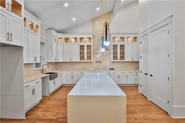 kitchen featuring decorative backsplash, white cabinetry, a center island, and pendant lighting