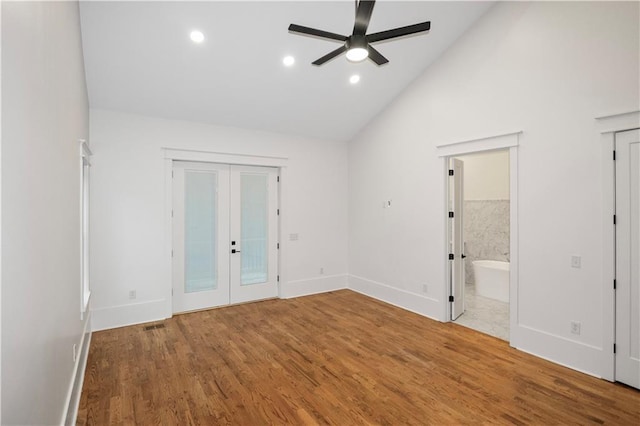 unfurnished bedroom featuring high vaulted ceiling, french doors, ensuite bathroom, hardwood / wood-style flooring, and ceiling fan