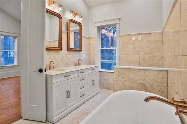 bathroom with a washtub, tile patterned flooring, lofted ceiling, vanity, and tile walls