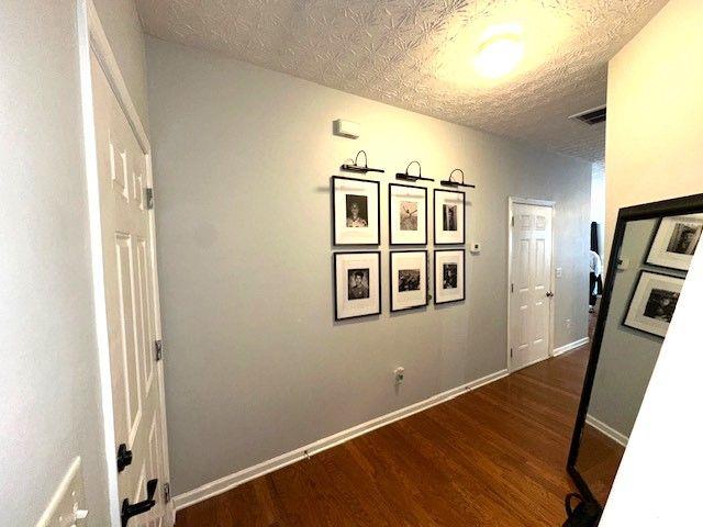 hall featuring a textured ceiling and dark hardwood / wood-style flooring