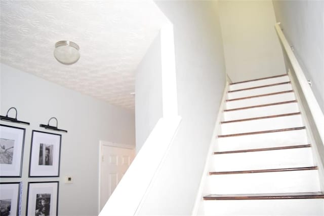 staircase featuring a textured ceiling