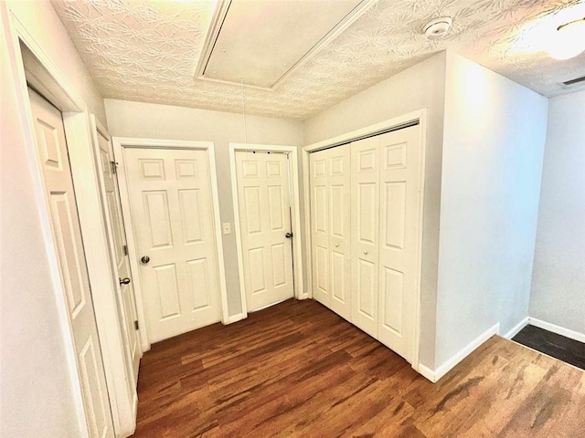 hall with a textured ceiling and dark hardwood / wood-style floors