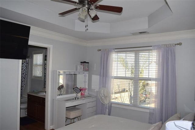 interior space featuring toilet, crown molding, a raised ceiling, vanity, and ceiling fan