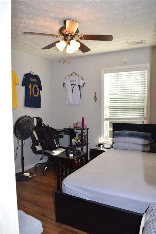 bedroom featuring a textured ceiling, dark hardwood / wood-style floors, and ceiling fan