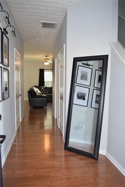 hall featuring dark wood-type flooring and a textured ceiling