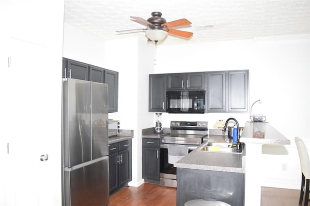 kitchen with ceiling fan, a textured ceiling, sink, dark hardwood / wood-style flooring, and stainless steel appliances