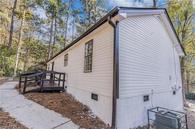 view of home's exterior with crawl space, a wooden deck, and central AC unit