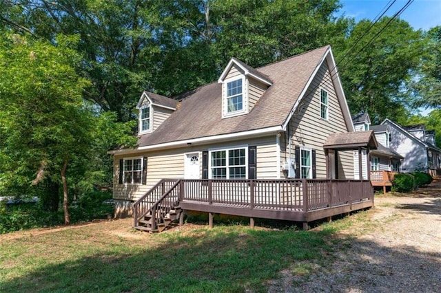 cape cod house with a wooden deck and a front lawn