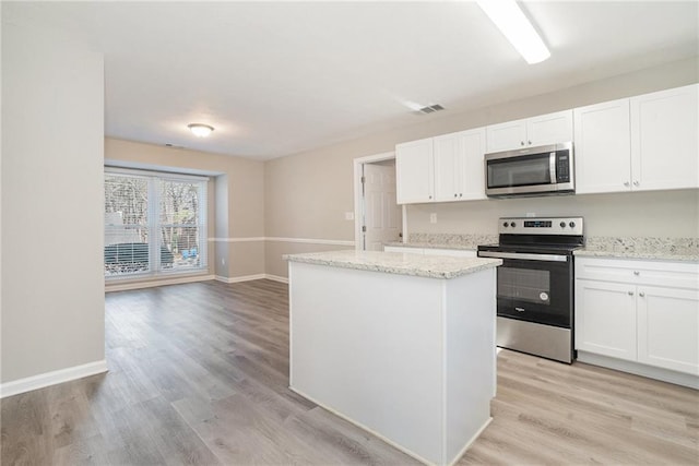 kitchen featuring white cabinetry, a kitchen island, light stone counters, and appliances with stainless steel finishes