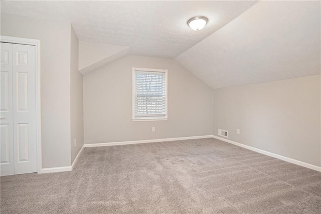 bonus room with carpet flooring, a textured ceiling, and vaulted ceiling