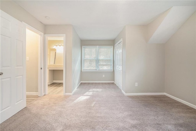 unfurnished bedroom with ensuite bath and light colored carpet