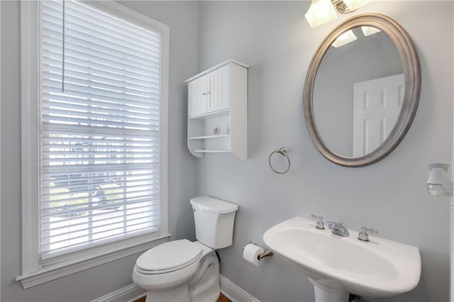 half bathroom with a sink, toilet, and baseboards