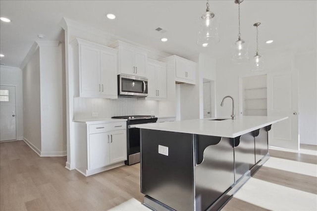 kitchen featuring sink, white cabinetry, pendant lighting, a kitchen island with sink, and appliances with stainless steel finishes