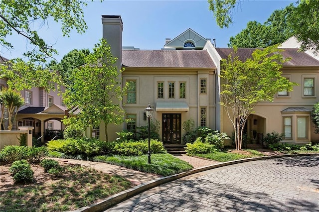 townhome / multi-family property with a chimney and stucco siding