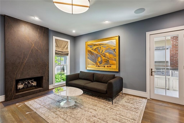 living room with a high end fireplace, recessed lighting, and wood finished floors