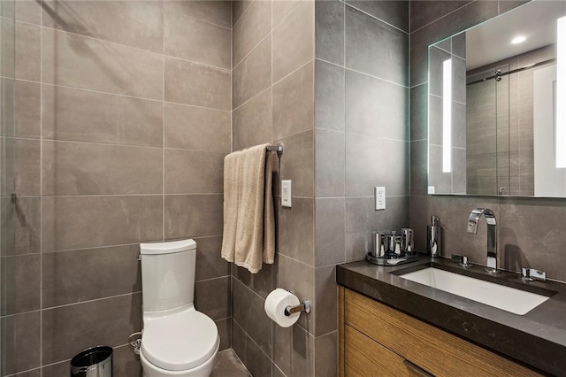 bathroom featuring tile walls, toilet, and vanity