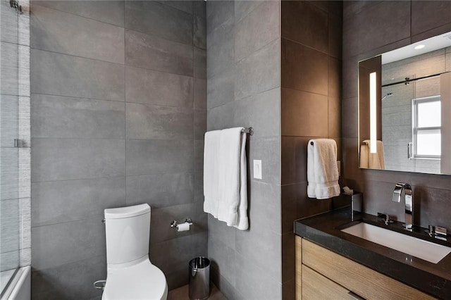 bathroom featuring toilet, walk in shower, tile walls, and vanity