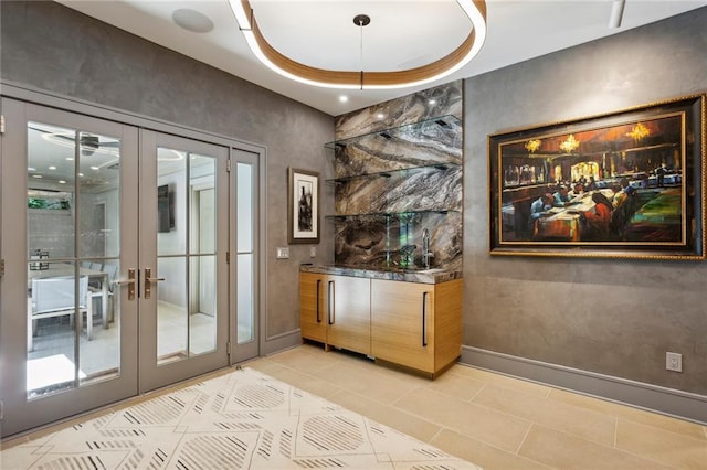 bar with a tray ceiling, french doors, baseboards, and light tile patterned floors