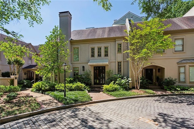 multi unit property featuring a chimney and stucco siding