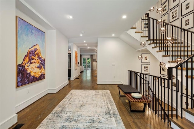 hallway featuring baseboards, wood finished floors, and recessed lighting