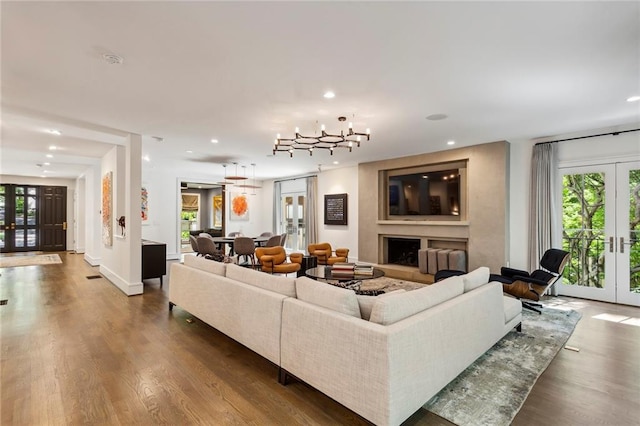 living area with a fireplace with raised hearth, french doors, and wood finished floors