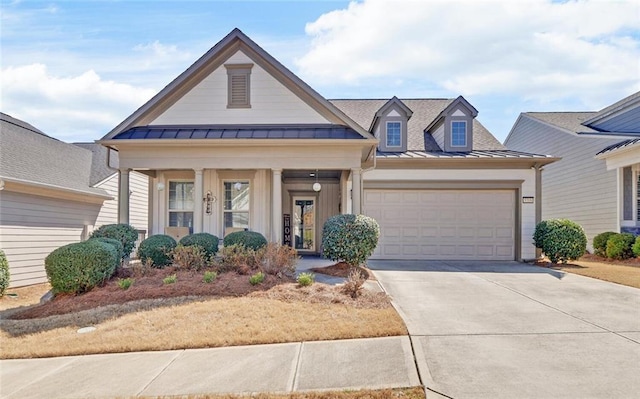 view of front of property featuring a standing seam roof, an attached garage, driveway, and metal roof