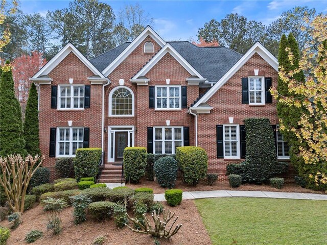 colonial house featuring brick siding and a front yard