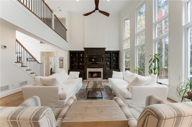 living area with visible vents, wood finished floors, ceiling fan, and a healthy amount of sunlight