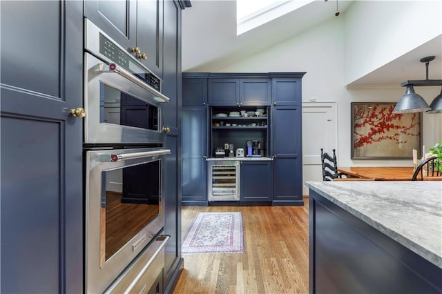 657 E Paces Ferry Rd NE, Atlanta, GA 30305 - indoor dry bar featuring wine cooler, stainless steel double oven, light wood-style flooring, decorative light fixtures, and high vaulted ceiling