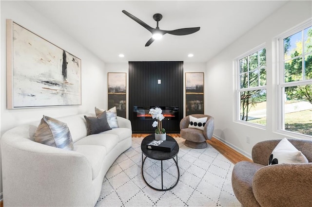 living room with a large fireplace, light hardwood / wood-style floors, and ceiling fan