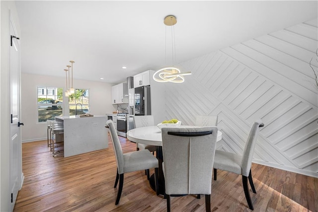 dining area with hardwood / wood-style flooring, sink, and an inviting chandelier