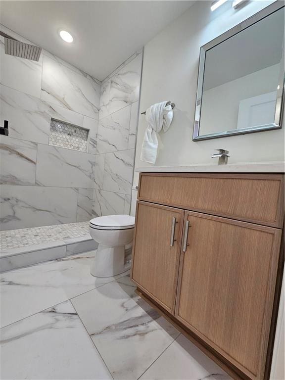 bathroom with tiled shower, vanity, and toilet