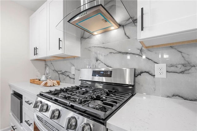 kitchen featuring white cabinetry, light stone countertops, stainless steel gas range, tasteful backsplash, and range hood