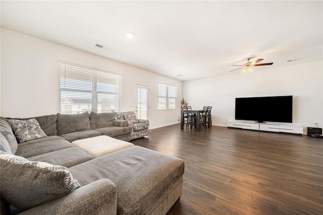 living area featuring baseboards, visible vents, ceiling fan, and dark wood-style flooring